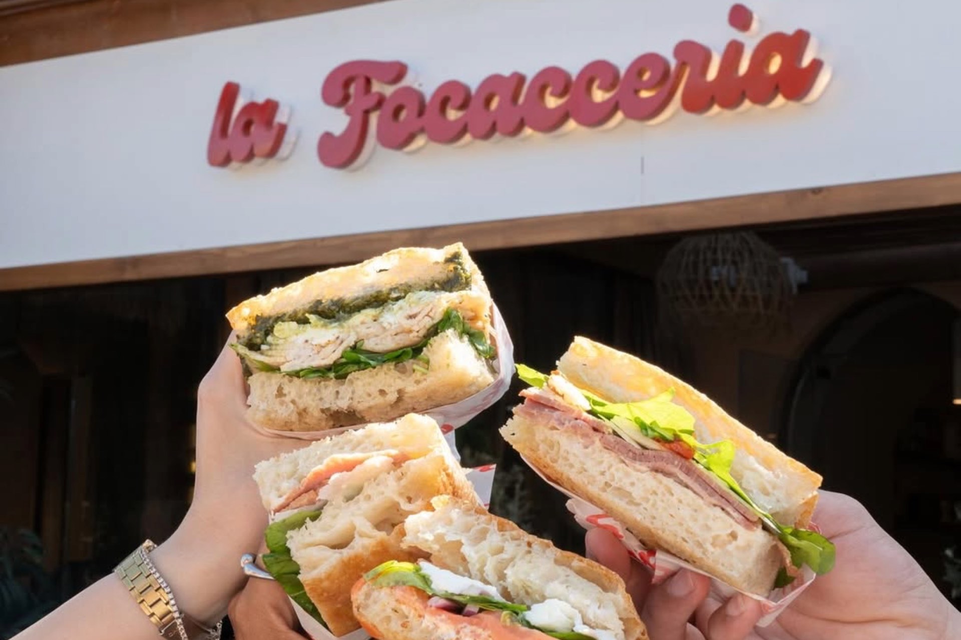 Three focaccia sandwiches held up in front of the La Focacceria storefront in El Gouna